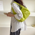 Detail of lime green ruched shoulder bag worn by model with minimalist style - Green