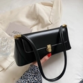 Elegant black leather baguette bag with gold metal buckle on a minimalist beige blazer - Black