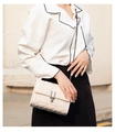 Detail van beige gewatteerde crossbodytas met donkergrijze metalen sluiting en ketting - Wit