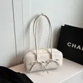 Detailweergave van glanzende crème Boston-tas met decoratieve strikaccenten en dubbele riemen - Wit