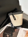 Detail view of canvas bucket bag with black leather trim resting on a black chair - Black