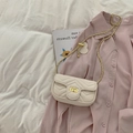Detail of cream quilted crossbody bag featuring V-shaped texture and gold hardware - White