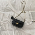 Detailed top view of black quilted crossbody bag with gold chain strap on white fabric - Black