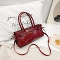 Dunkelrote Lackleder-Boston-Tasche mit Tragegriffen und Schultergurt in Lifestyle-Szene - Burgunderrot
