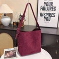 Bolso tote grande de ante burdeos con correa ancha en un ambiente interior minimalista - Burdeos