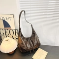 Vintage bruine grote hobo tas met verstelbare riem op een minimalistisch bureau - koffiekleur