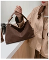 Detail of dark brown suede handbag with golden hardware held by model in trench coat - Coffee