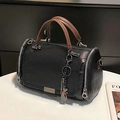 Zwarte Boston tas met bruine handvatten en kattenhanger op een witte tafel - Zwart