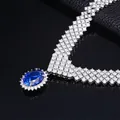 Detailed macro of a luxury necklace with a large oval blue gemstone and pavé diamonds - Lab-grown Sapphire Style (NL024674-B)