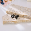 Minimalist matte black stainless steel hoop earrings for men on stone display blocks - Black