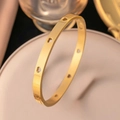 Detalle de una pulsera de acero inoxidable dorada con diseños de corazones huecos - Brazalete Corazón Calado / Dorado
