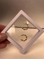 Dettaglio di un orecchino a cerchio a perline dorate in una scatola espositiva bianca - Oro