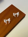 Detailed close-up of silver bow earrings featuring a textured metallic brushed finish - Silver