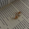 Boucles d'oreilles élégantes en or avec perles et zircons sur page de livre - Doré
