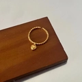 Detail eines vergoldeten gedrehten Rings mit Herzanhänger auf Holzuntergrund - Gold