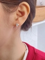 Detalle de un pendiente de corazón en plata 925 con circón usado por una mujer real - Plateado