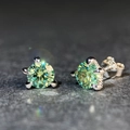 Dettaglio macro di orecchini a lobo in moissanite verde tonda con tre griffe argento - Verde Pavone