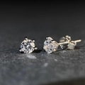 Primo piano di orecchini a lobo in argento 925 e moissanite con classica incastonatura a quattro griffe - Bianco Colore D