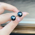 Primo piano di orecchini con perle nere di Tahiti lucide tenuti in mano per la misura - 8mm / Grigio