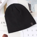 Black knitted beanie hat with star leather patch on a minimalist magazine background - One Size (56-59cm) / Black