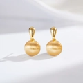 Macro detail of 24K gold-plated drop earrings featuring a matte brushed metal sphere - Round (ED220-T)