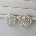 Detail of silver beaded tassel earrings featuring sleek metallic fringe on linen background - Silver