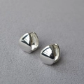 Macro shot of polished silver teardrop earrings with a smooth mirror finish on fabric - Silver