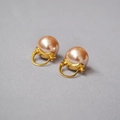 Orecchini dorati eleganti con perle rosa tonde su sfondo di tessuto grigio - Perla Champagne