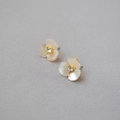 Close-up of golden clover stud earring with white shell petals and central crystal - Stud Earrings