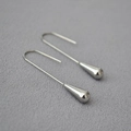 Dettaglio macro di orecchini a goccia color argento con eleganti ganci lunghi - Oro Bianco