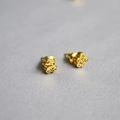 Gros plan sur des boucles d'oreilles ours dorées avec une texture en métal martelé - Nuage