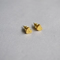 Vue macro de boucles d'oreilles cœur dorées avec texture martelée sur fond de tissu gris - Cœur
