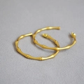 Dettaglio di orecchini a cerchio in oro stile bambù con finitura opaca su tessuto - Oro Satinato Vintage