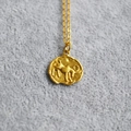 Detailed macro view of vintage gold coin pendant with embossed zodiac bull motif on chain - Capricorn