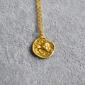 Macro shot of gold Leo zodiac relief pendant on a minimalist thin chain necklace - Lion