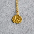 Macro detail of gold Gemini zodiac coin pendant necklace with embossed coin relief - Gemini