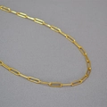 Macro di una collana a catena a graffetta dorata minimalista con trama in metallo lucido - Maglia Grande alla Moda Oro