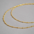 Dettaglio della catena in ottone placcato oro 18 carati con piccole perle dorate lucide - Collana a Doppio Strato con Perline / Oro