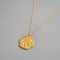 Dettaglio ravvicinato di un ciondolo a moneta d'oro irregolare con goffratura vintage - Stile Piccola Moneta