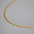 Collana a catena Figaro minimalista in oro 18K su uno sfondo grigio materico raffinato - Catena Figaro Dorata