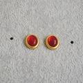Nahaufnahme der Vintage-Ohrstecker in Gold mit ovalem rotem Edelstein auf grauem Samt - Rot