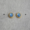 Detailaufnahme von Retro-Ohrsteckern in Gold mit ovalen blauen Edelsteinen auf grauem Grund - Blau