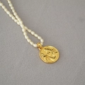 French vintage freshwater pearl necklace with a detailed gold coin pendant on gray fabric - Dove Girl
