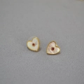 Detail van hartvormige oorknopjes met wit parelmoer en een rode edelsteen in het midden - Hart Rode Zirconia Oorknopjes