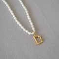 Macro shot of freshwater rice pearl necklace with a bamboo texture gold letter D pendant - Letter D