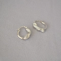Detalle de pendientes de aro con nudo plateado y pavé de piedras de circonita cúbica - Plateado