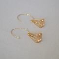 Dettaglio degli orecchini a piramide dorati con intarsi in cristallo color champagne - Oro + Zirconia Champagne
