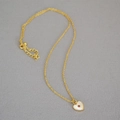 Close-up of golden heart pendant with white shell inlay and red zircon center gemstone - Gold Chain Red Heart Pendant