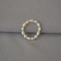 Detailaufnahme von 13 natürlichen weißen Reisperlen auf einem elastischen Band für Ringe - Einheitsgröße / Elastischer Stil / Perlweiß