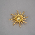 Dettaglio di una spilla dorata per cappotto con raggi di sole lucidi radianti - Oro
